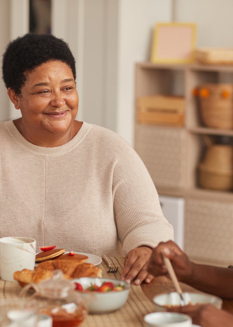 black woman smiling at someone while eating breakfast