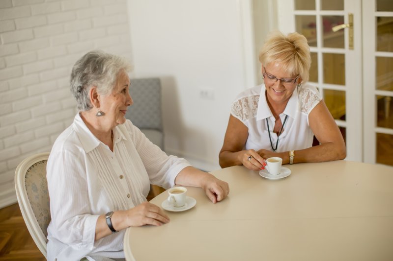 Elderly woman and daughter enjoying tea and visiting