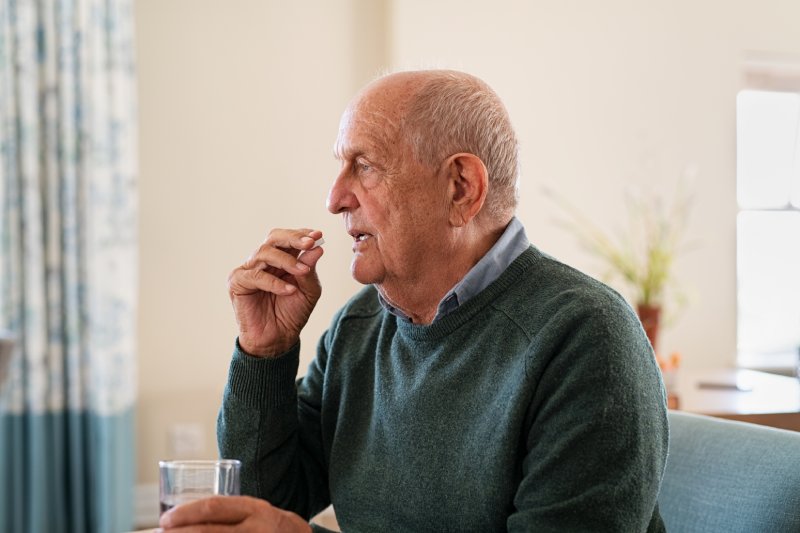 elderly man taking medication with water